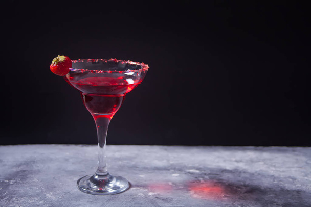 Romantik yemek için beton zeminde berrak bardakta kırmızı egzotik alkollü kokteyl.. - Fotoğraf, Görsel
