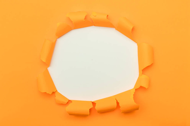 Orange paper with ripped hole in the middle background - Photo, Image