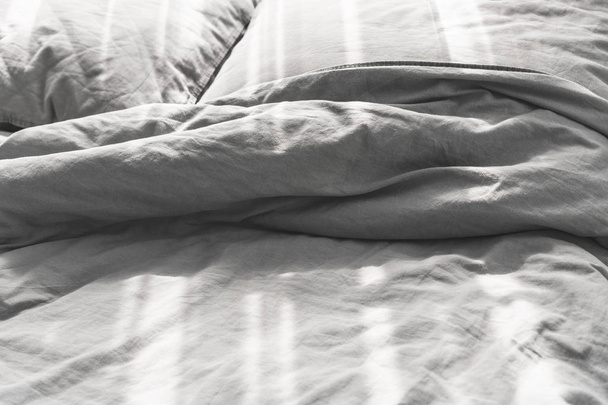 Cama desordenada sin hacer con dos almohadas, ropa de cama gris
 - Foto, Imagen