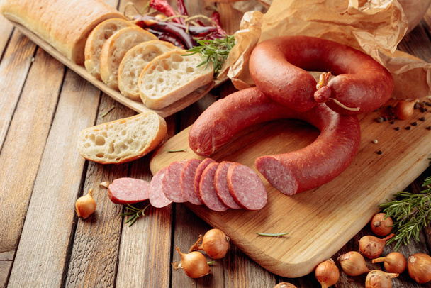 Smoked sausage with bread and spices on a old wooden table. - 写真・画像