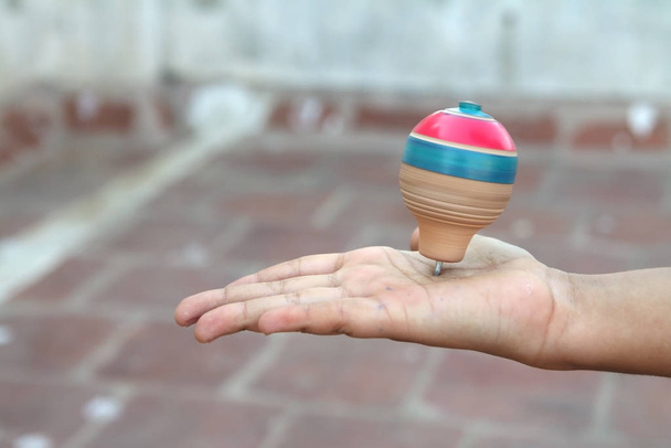 Clássico brinquedo top giratório de madeira sobre a palma da mão
 - Foto, Imagem