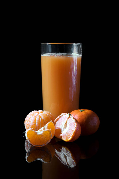 orange juice in a glass and tangerines on a black background - Photo, Image