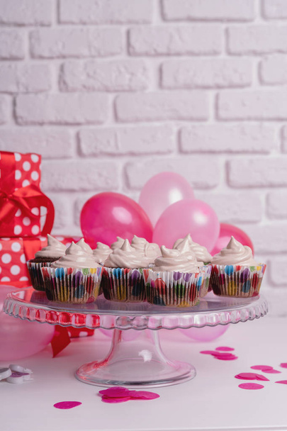 colorati cupcake di compleanno con coriandoli e palloncini su sfondo di mattoni bianchi
 - Foto, immagini