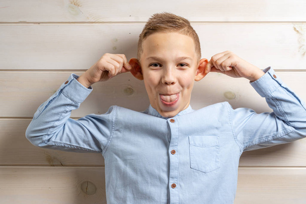 Un ragazzo di 10 anni con una camicia blu sorride su una leggera b di legno
 - Foto, immagini