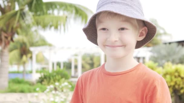 A jó fiú szőke mutatja osztály hátterében zöld pálmafák és egy medence. - Felvétel, videó