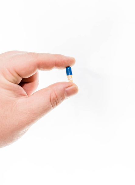 Hand holding antibiotics capsules or painkillers isolated on whi - Photo, image