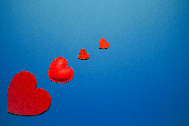 Decorative felt hearts on blue background. Abstract backdrop wit - 写真・画像