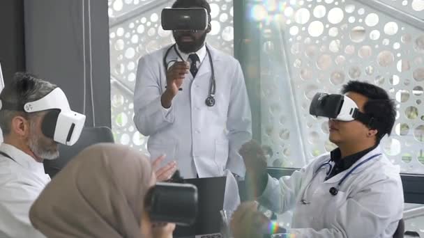 Professional likable african american doctor working with virtual reality glasses together with his multiracial doctors-colleagues in medical office - Filmati, video