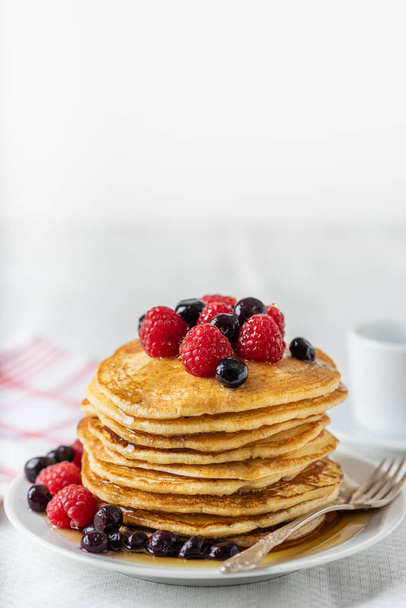 Sweet homemade pancakes with raspberries and blueberries on white plate. - Fotó, kép