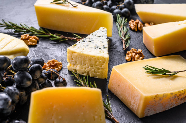 Différents types de délicieux fromages aux noix et raisins. Fond noir. Vue du dessus - Photo, image
