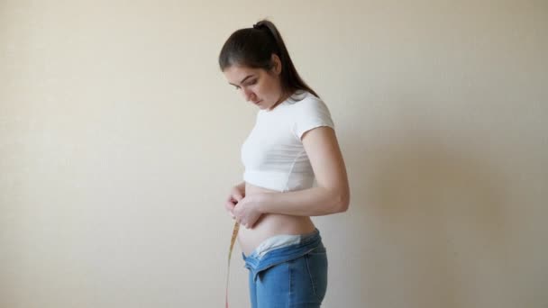 Dagadt nő végez méréseket a derék egy centiméter szalaggal - Felvétel, videó