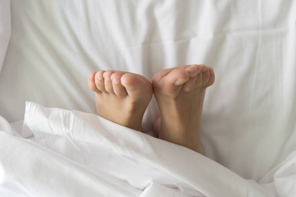 Two feet in a bed against a white background - Φωτογραφία, εικόνα