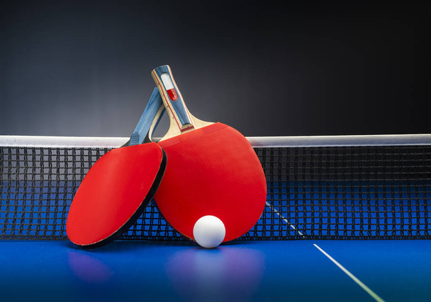 Raquettes et balles de ping-pong sur une table bleue avec filet
. - Photo, image