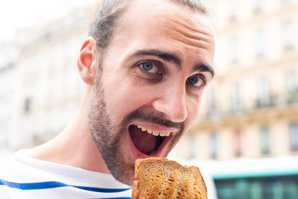 Close up retrato de jovem comendo sanduíche fora na cidade
 - Foto, Imagem
