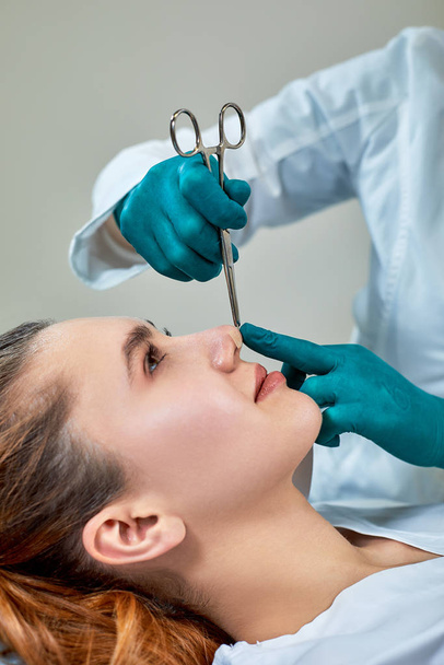 鼻の上に石膏を持つ女性医師試験の患者の顔の整形手術後 - 写真・画像