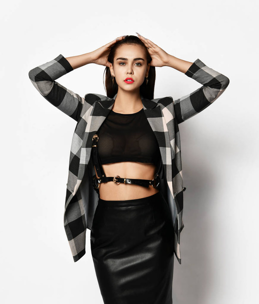 Young glamorous modern girl in a checkered jacket and black skirt wear red fashion glasses posing  - Photo, image