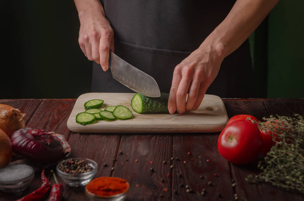 Mooie vrouwelijke handen snijden een verse komkommer op een houten plank. C - Foto, afbeelding