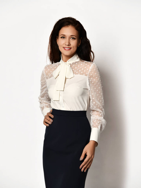 Beautiful brunette girl in casual white office blouse with ruffles tulle on a gray - Fotó, kép