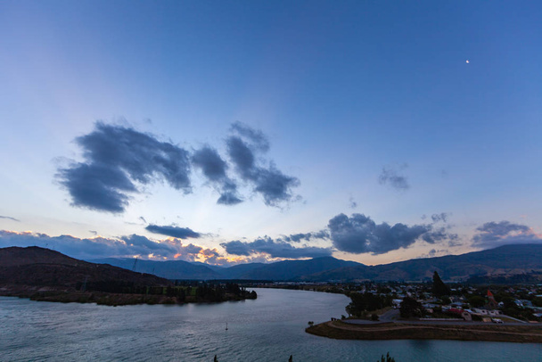 Пейзаж с высокими скалами с подсвеченными персиками, камнями в горном озере, голубым небом и желтым солнечным светом на рассвете.  - Фото, изображение