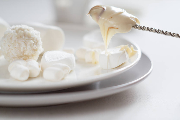 Various white candies, marshmallows and peanut butter on a light background - Фото, зображення