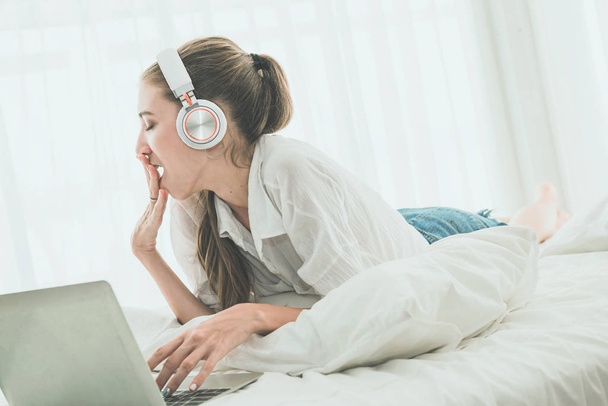 Mujer joven en el dormitorio con ordenador portátil, bostezo y failli
 - Foto, Imagen