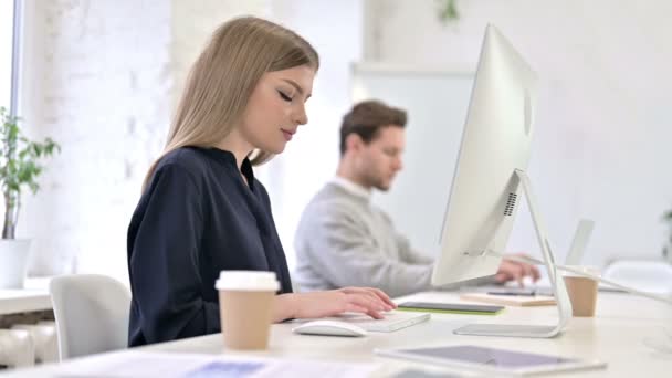 Keskittynyt luova nainen työskentelee työpöydällä modernissa toimistossa
  - Materiaali, video