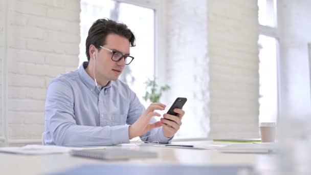 Attractive Working Young Man Listening to Music on Smartphone  - Footage, Video
