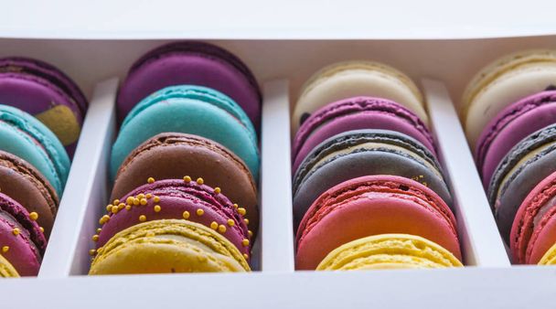 Set of different french cookies macaroons macaroons in a paper box. Top view. Any tastes. Coffee, chocolate, vanilla, lemon, rapsberry, strawberry, pistachio, violet, rose, orange tastes macaroons - Photo, image