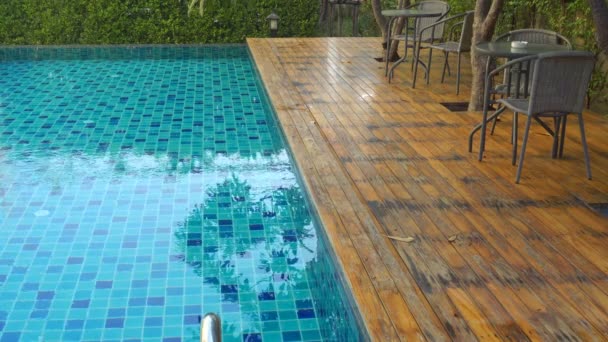 The surface of a swimming pool or water texture Ocean. Which has a table and chair set for relaxing under the tree - Footage, Video
