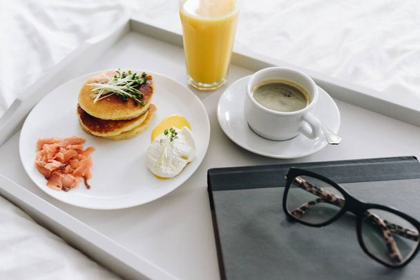 Close up de café da manhã nutritivo e saboroso com café na cama na bandeja com óculos e livro
 - Foto, Imagem