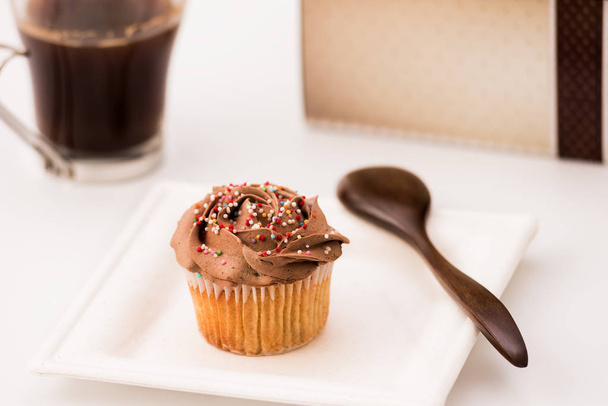 Muffins au chocolat sur fond blanc avec une tasse de café et une cuillère en bois. Cuisson maison, mise au point sélective, gros plan
. - Photo, image