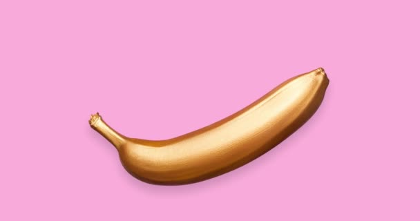 Stop motion animation with golden metallic banana on a pink background. A modern creative concept. Contemporary art - Video, Çekim