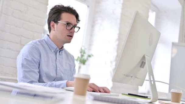 Gericht werkende jonge man drinken koffie en het gebruik van Desktop - Video
