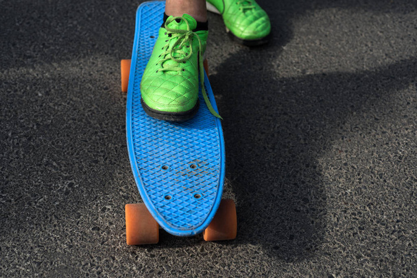 Summer activities. Male sport shoe standing on blue penny board on summer day. Enjoying summer sport outdoor. Skateboarding or travelling on short summer cruiser - Valokuva, kuva