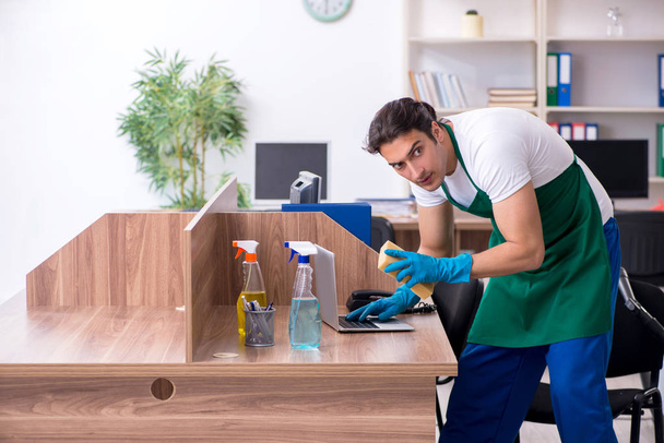 Joven contratista guapo limpiando la oficina - Foto, Imagen
