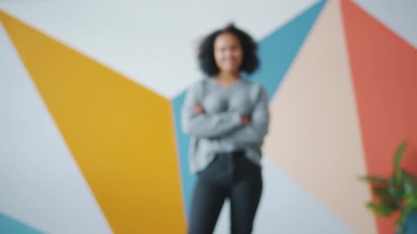 Увеличенный портрет привлекательной афро-американской девушки, стоящей в помещении и улыбающейся
 - Кадры, видео