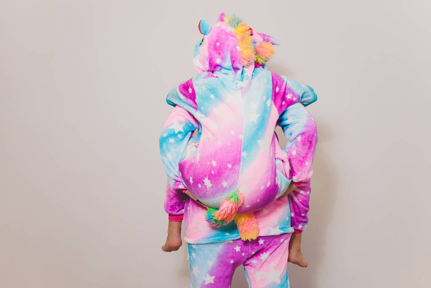 Una chica vestida con un disfraz de unicornio kigurumi, preparándose para la fiesta de cosplay o de pijamas. La joven vestida de pijama mirando a la cámara mientras posa sobre el fondo blanco
. - Foto, Imagen