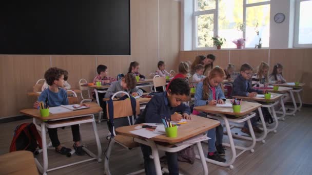 Różnorodne dzieci podczas lekcji rysunku w szkole - Materiał filmowy, wideo