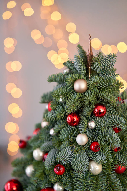 Gyönyörű kis karácsonyfa a fa asztalon. Boldog hangulatot. Garland lámpa bokeh a háttérben. Tapéta. Dán fenyő és fenyő, Nobilis - Fotó, kép