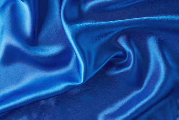 Blue silk background with a folds.  Abstract texture of rippled satin surface - Фото, зображення