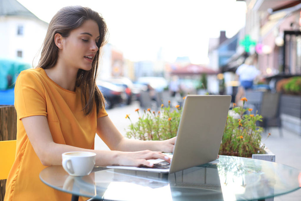 Smiling woman using laptop in cafe. Concept of entrepreneur, businesswoman, freelance worker. - Photo, Image