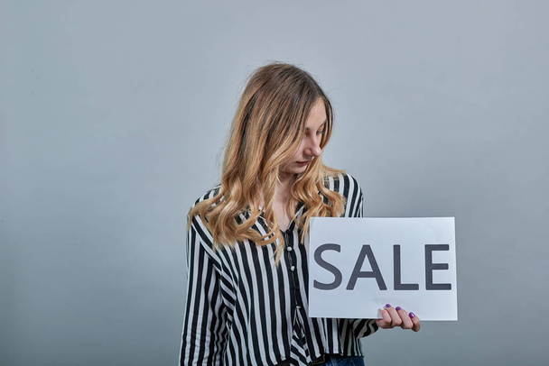 Curly caucasian young blonde woman keeping advertising blank sale, looking on it - Foto, Bild