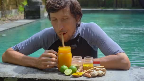 Mladý muž pije národní balijský nápoj Jamu koupající se v bazénu - Záběry, video