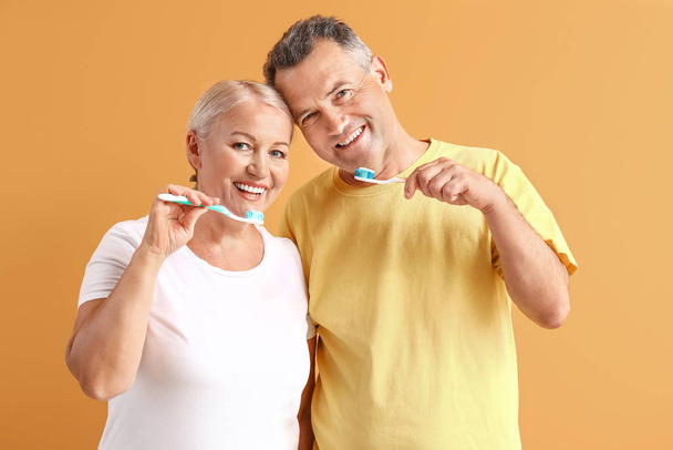 Couple mature brossant les dents sur fond de couleur - Photo, image