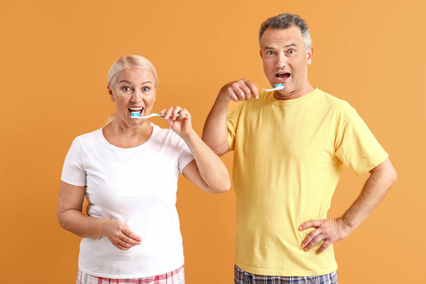 Couple mature brossant les dents sur fond de couleur - Photo, image