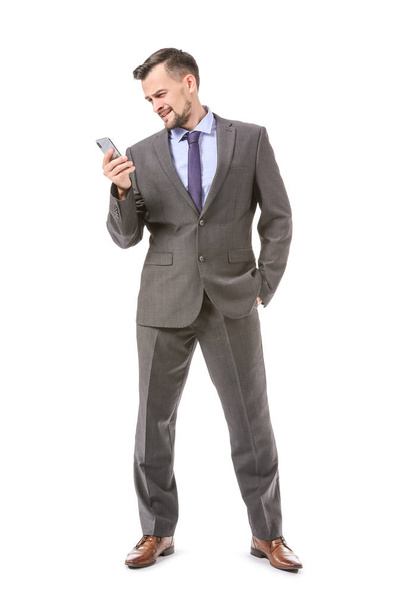 Portrait of handsome businessman with mobile phone on white background - Fotó, kép