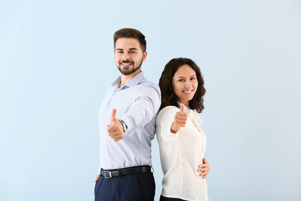Portrait of young business people showing thumb-up gesture on color background - Valokuva, kuva