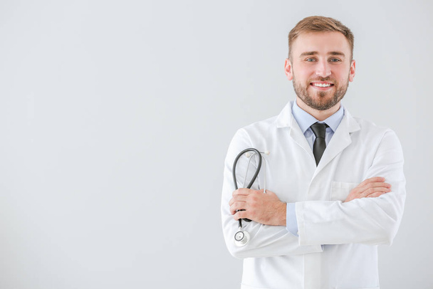Portret van een mannelijke arts met stethoscoop op lichte achtergrond - Foto, afbeelding