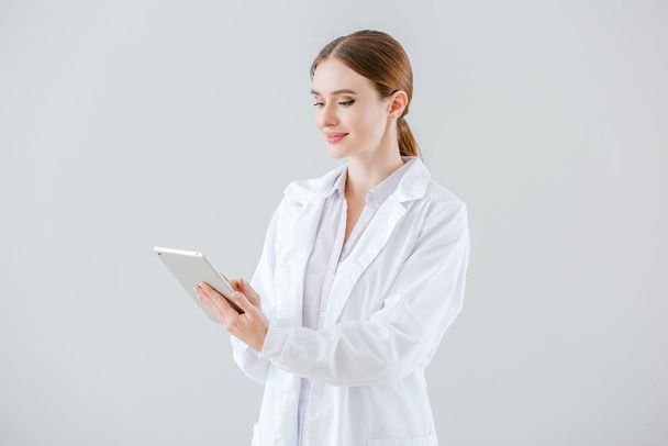 Portrait of female doctor with tablet computer on light background - Foto, Imagem