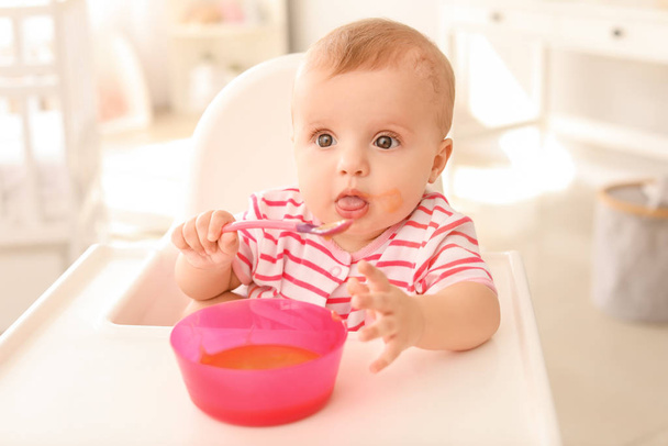 Portrait of cute little baby eating tasty food in kitchen - Φωτογραφία, εικόνα
